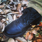 Close up of Chef's left foot wearing a  black Mozo Chef Shoe while stepping on a pile of leaves. 