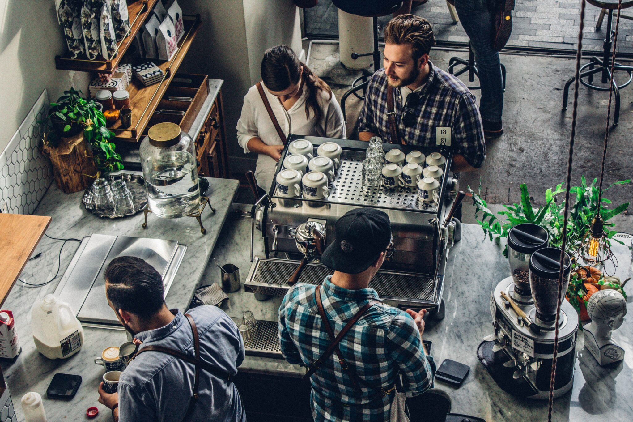 Man buying coffee on counter with two hospitality professionals serving them.